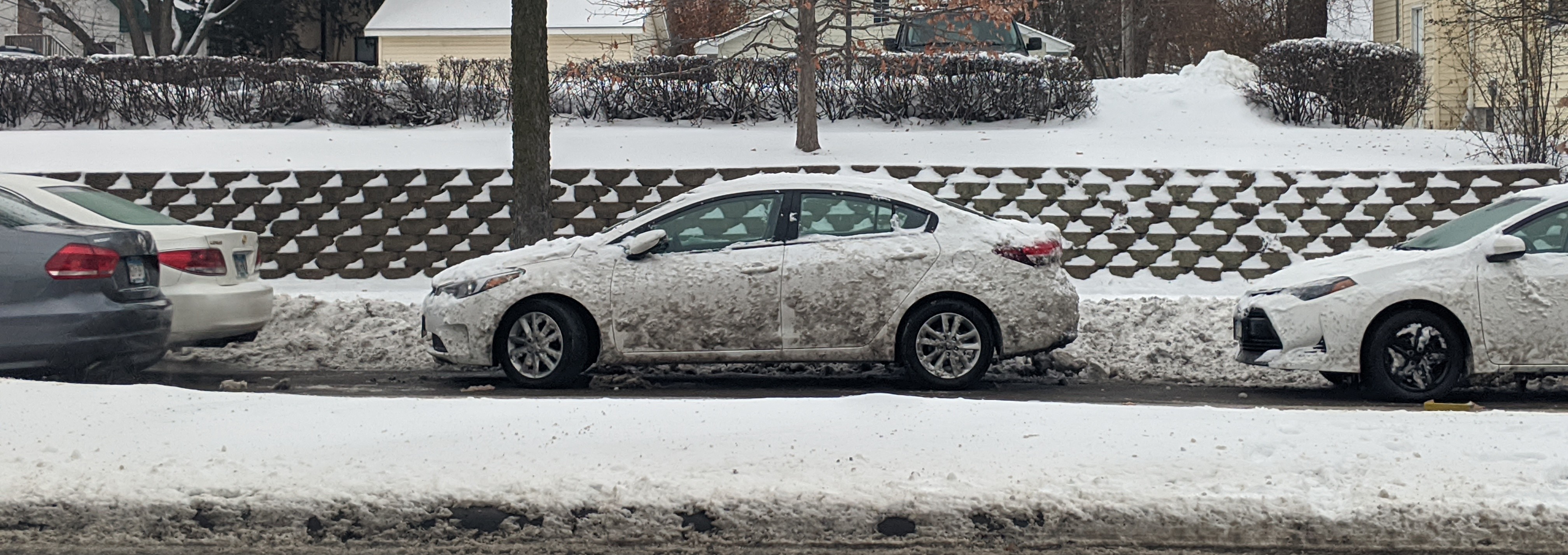 A once-white car, covered in snow and muck.
